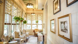 A room with patterned chairs, a dining table, and hanging plants.