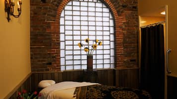 Relax in this stylish room with a large window, arched brick wall, and comfortable bed.