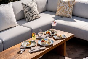 A dining area with a wooden table set for a meal, a sofa with patterned cushions, and a glass of drink. - JW Marriott Bucharest Grand Hotel (Bucharest)