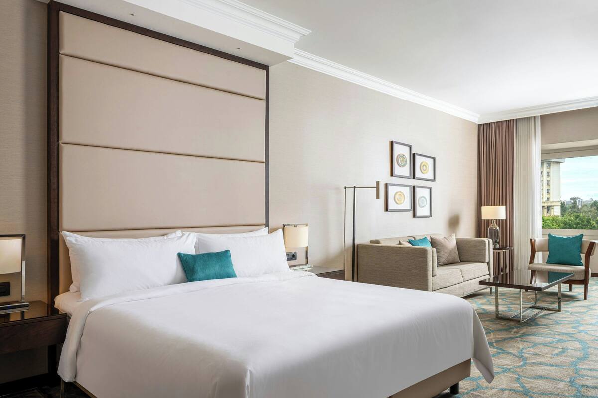 A hotel room with a large bed, a sofa, a chair, and a desk.
