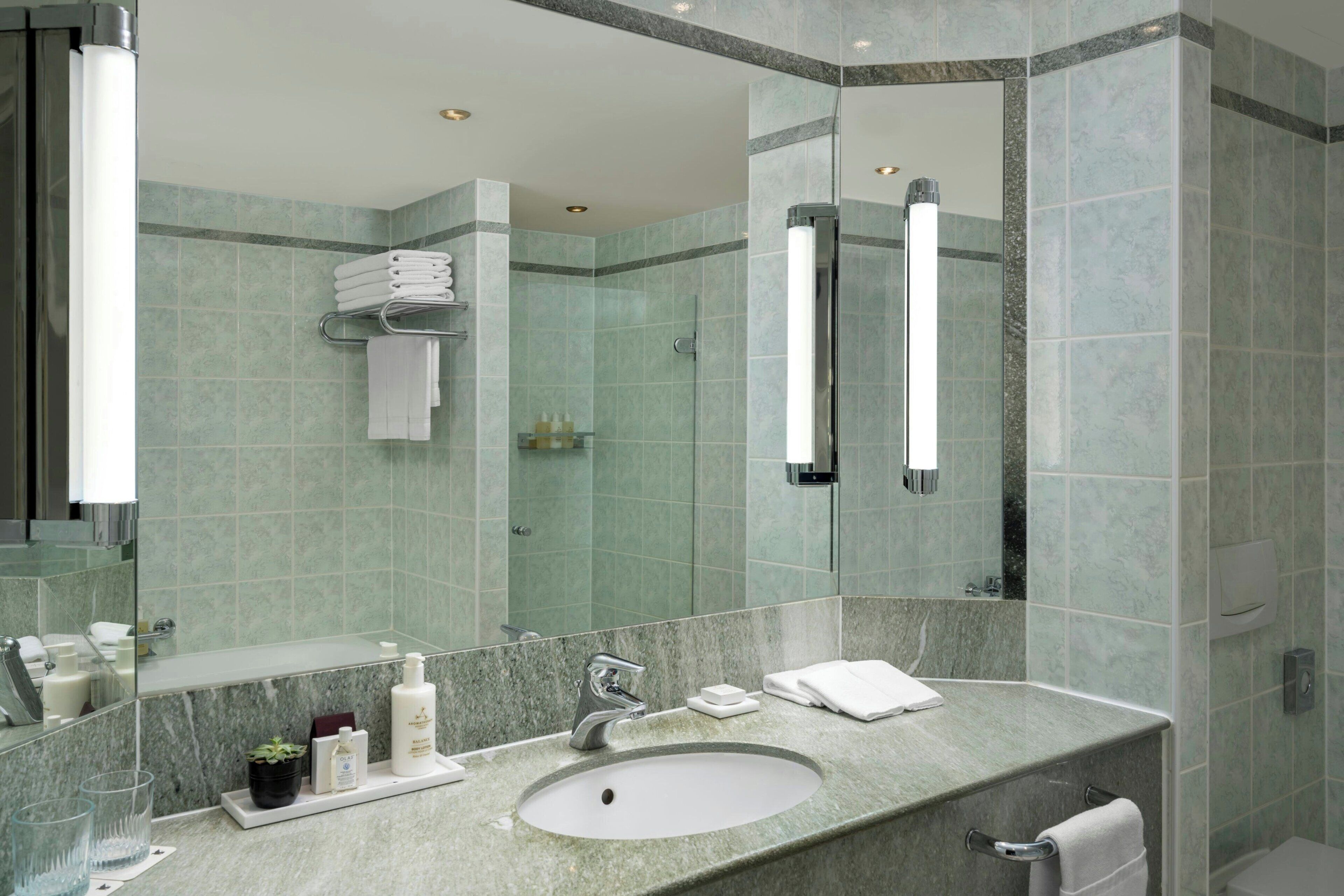 A modern bathroom with a large mirror, a sink, and a shower area.
