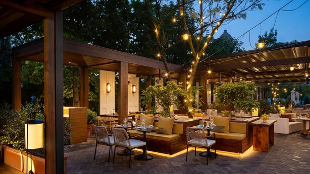 Een terras buiten met houten meubels, tafels en stoelen.