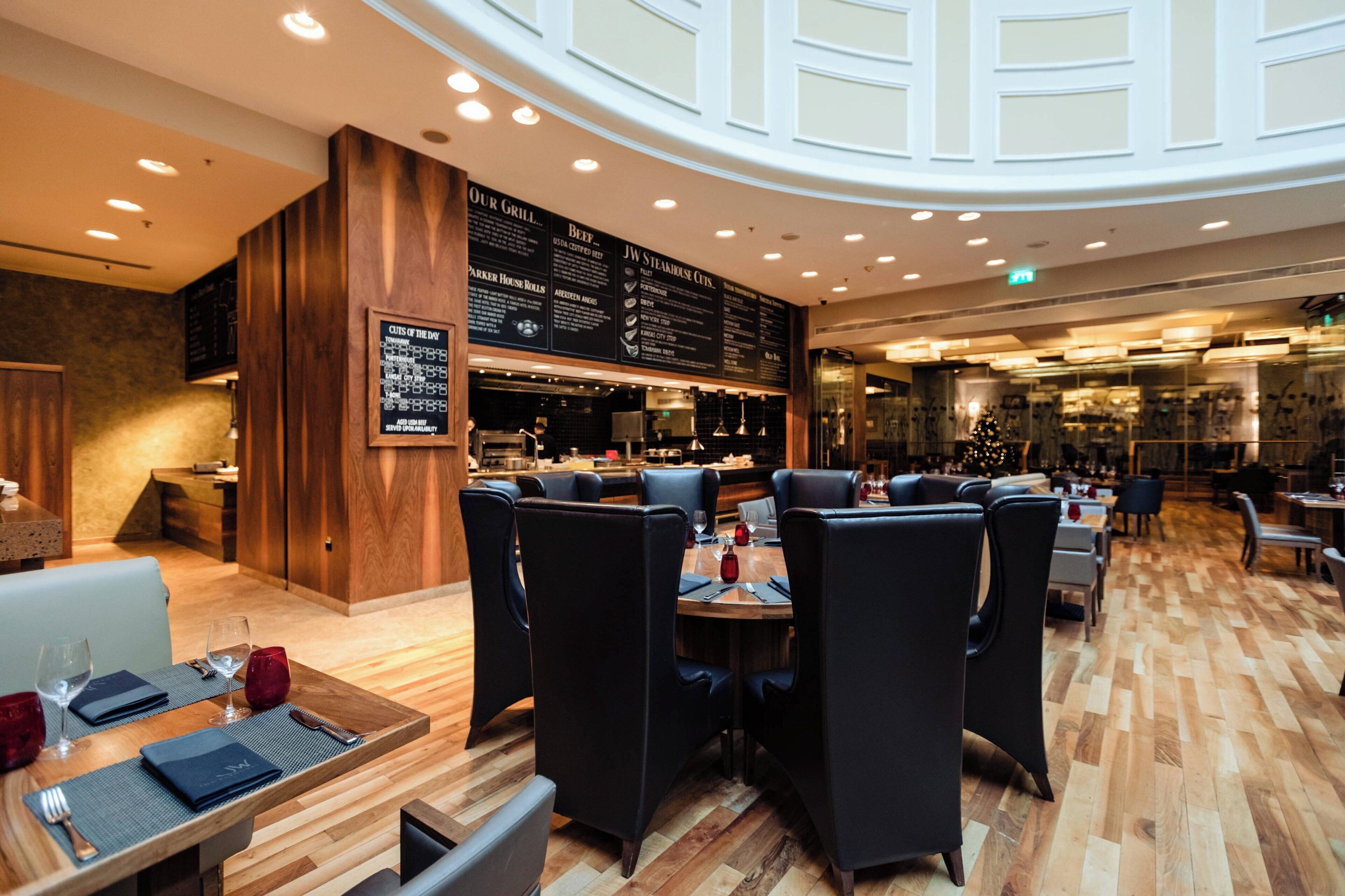 A restaurant with wooden flooring, black menu boards, and modern lighting.