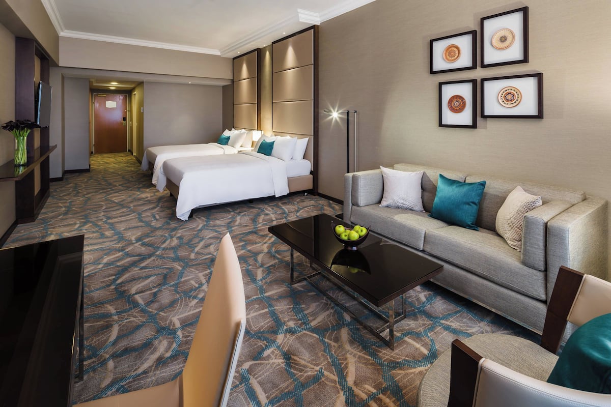 A hotel room with a large bed, a sofa, a coffee table, and a TV.