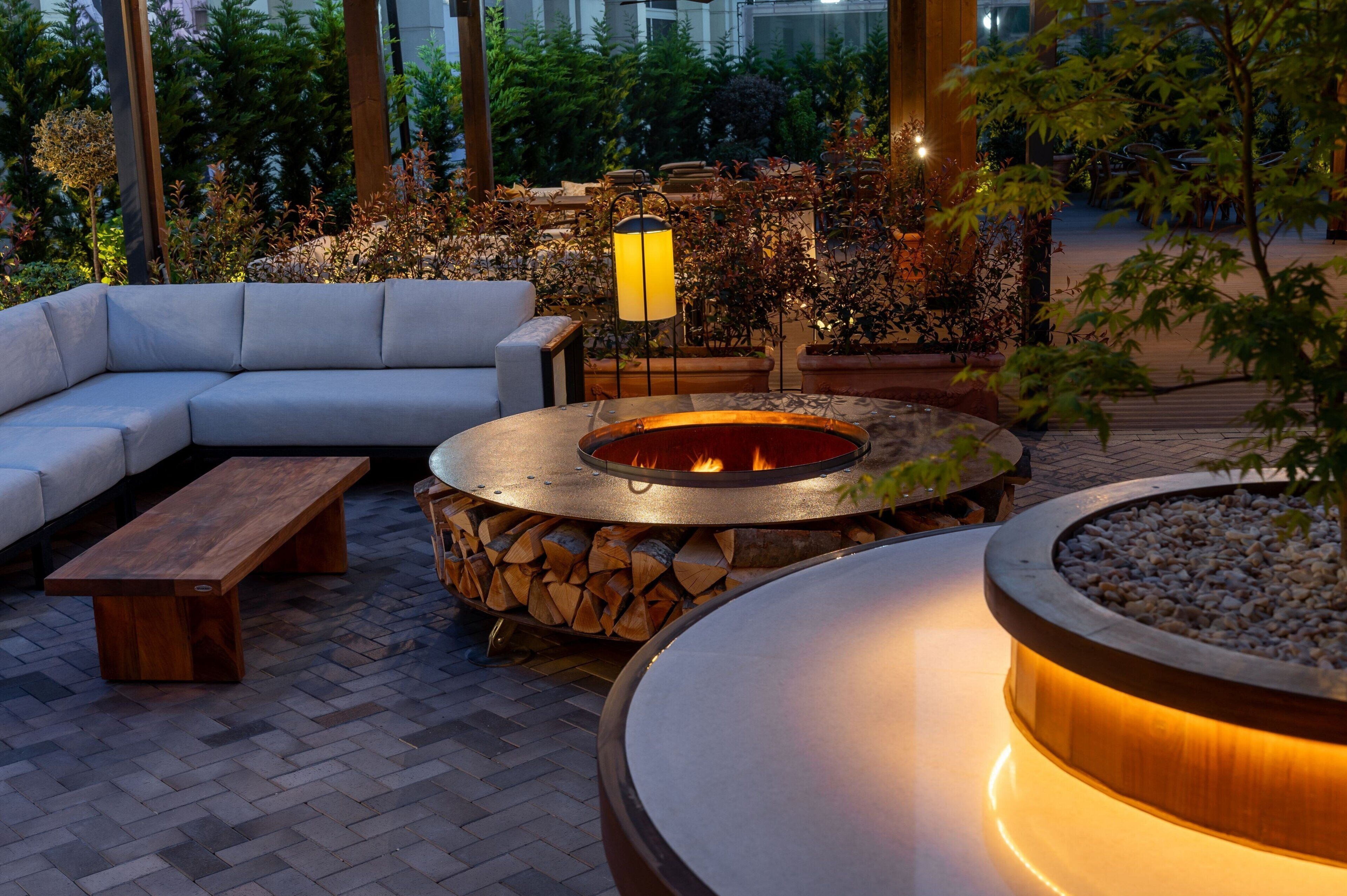 Un espacio al aire libre acogedor con una chimenea, un sofá y una mesa de madera.