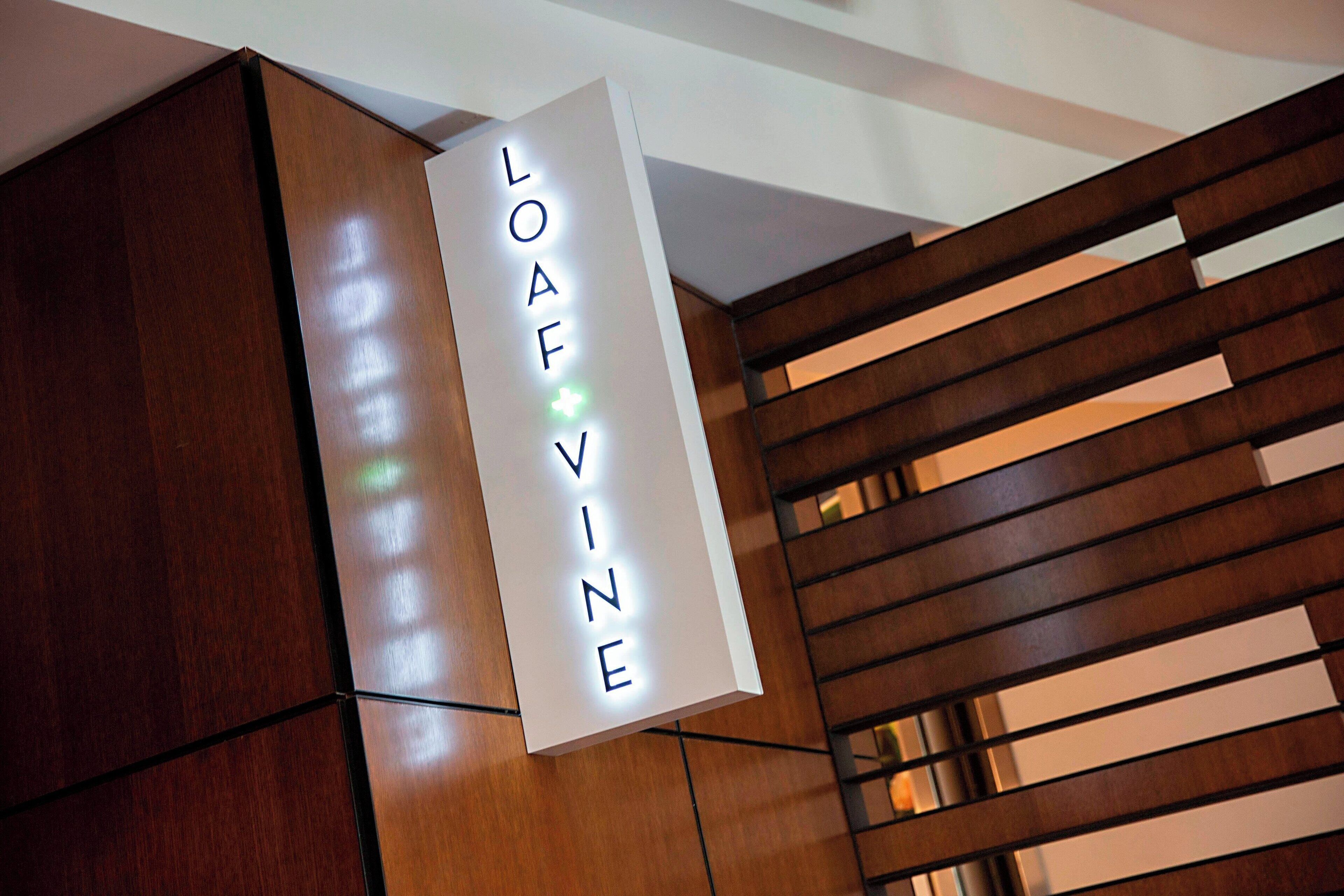 A sign with the name "LOAF VINE" in a modern, minimalist setting with wooden paneling and a slatted design.