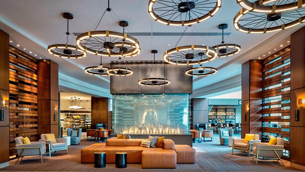 A modern lobby with circular ceiling lights, a central seating area, and a bar in the background. - Marriott Indianapolis Downtown (Indianapolis)