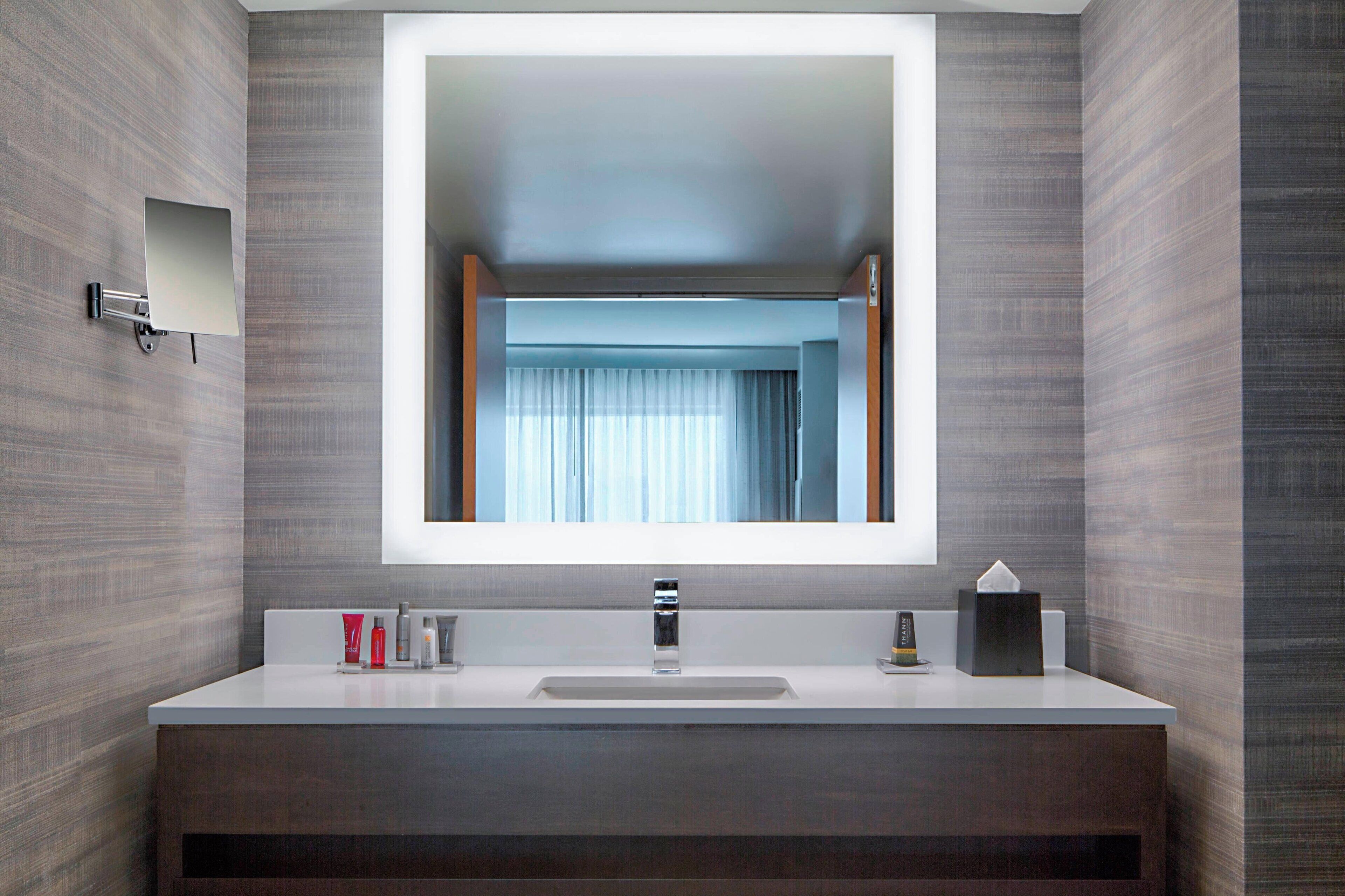 A modern bathroom with a large mirror, a sink, and a vanity.