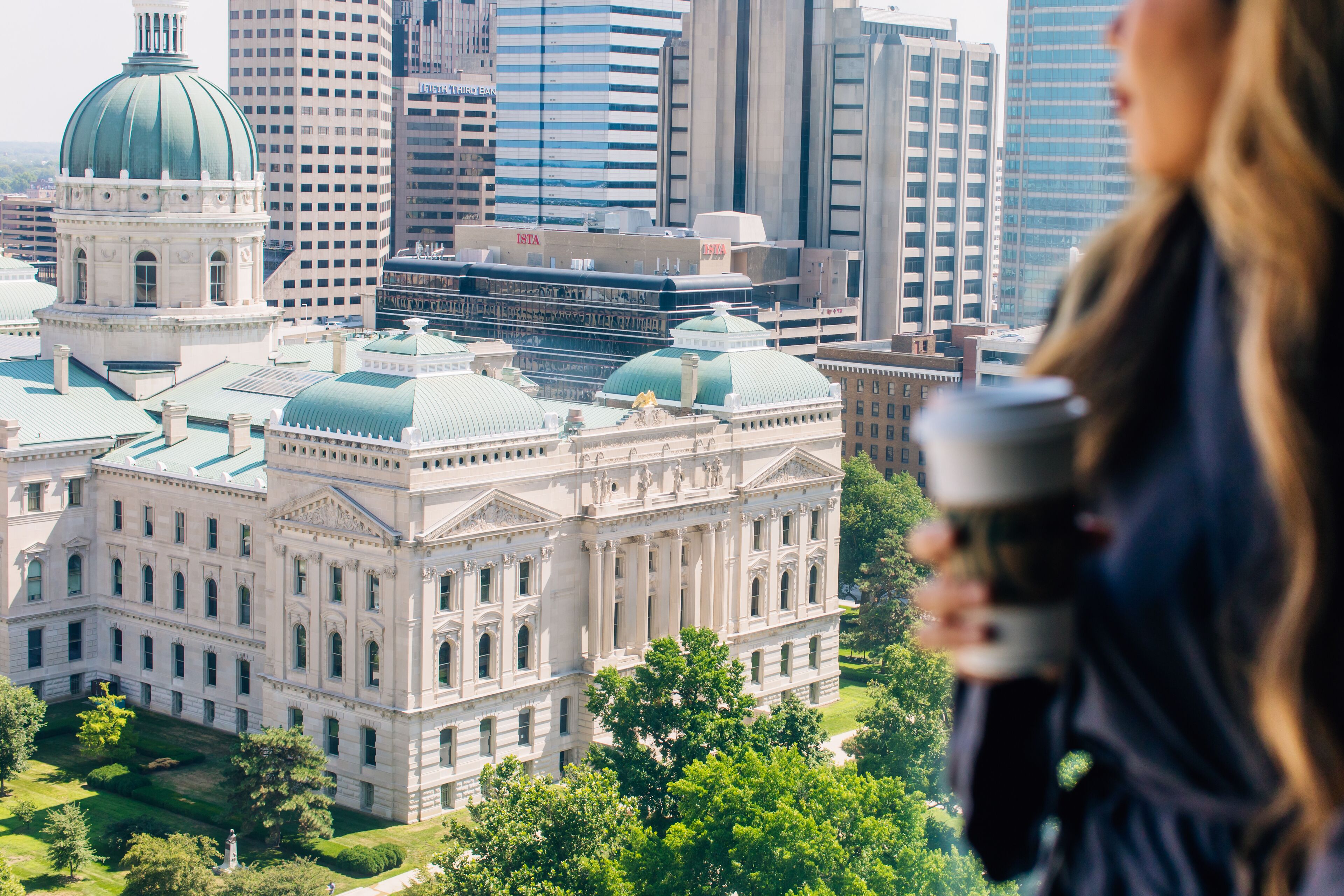 A large, historic building with a dome and classical architecture, surrounded by modern skyscrapers.