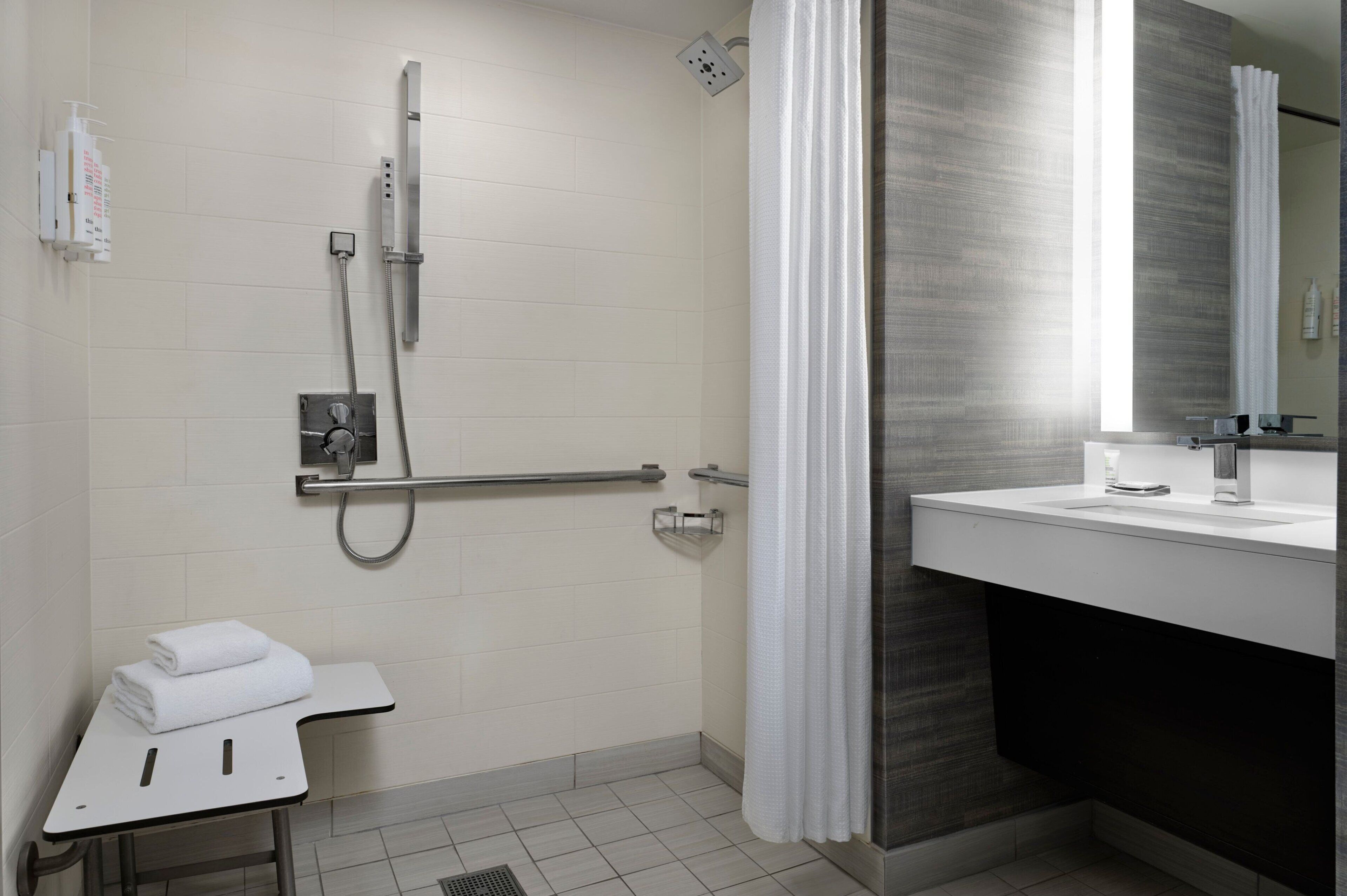 A modern bathroom with a shower, a vanity with a mirror, and a towel rack.
