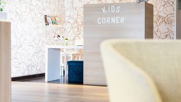 A children's corner area with a white reception desk and a blue bench.