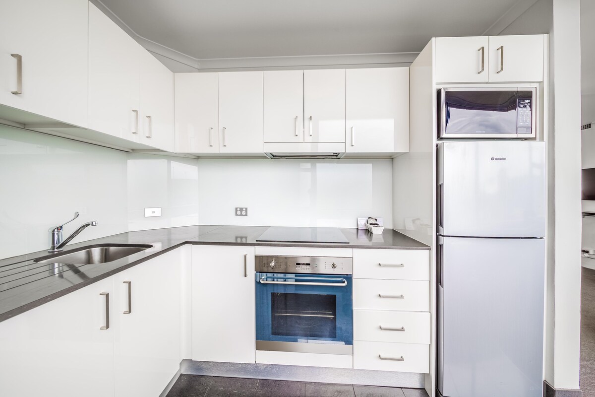 Een moderne keuken met witte kasten, roestvrijstalen apparatuur en een inbouwoven.