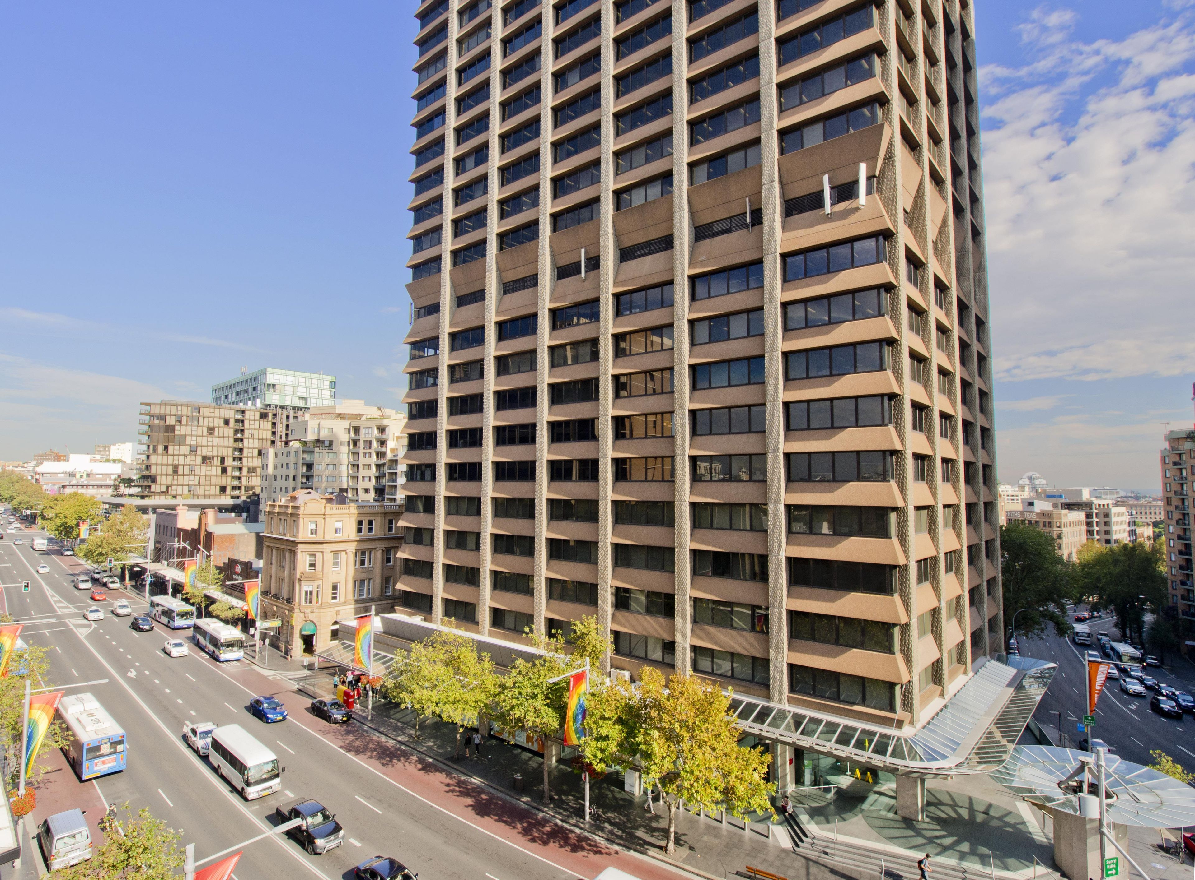 A high-rise building with a modern architectural design, featuring a prominent glass facade and a series of balconies.