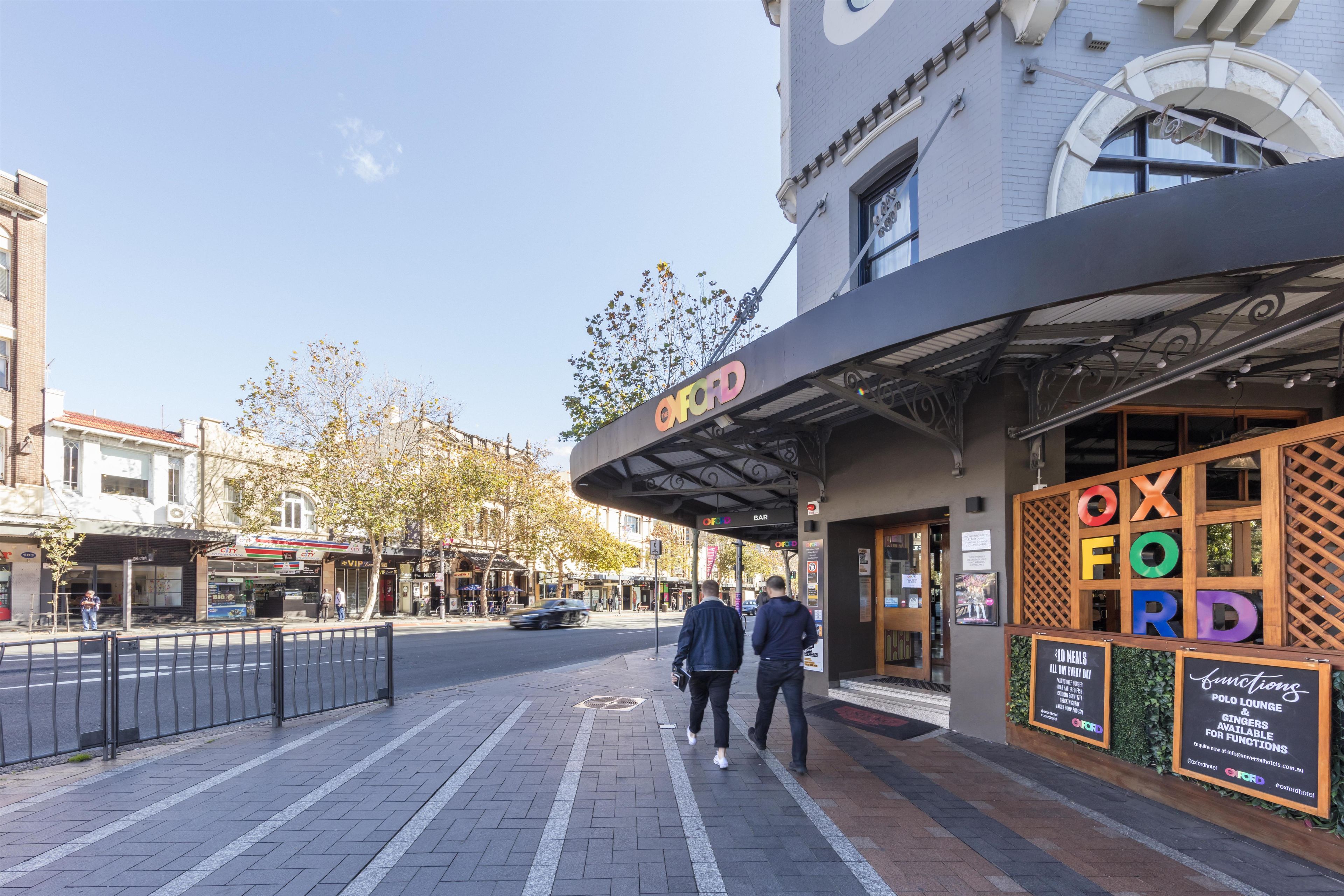 A street view with a building featuring a bar named 'OXFORD' and a sign advertising '10 MEALS ALL DAY EVERY DAY.'