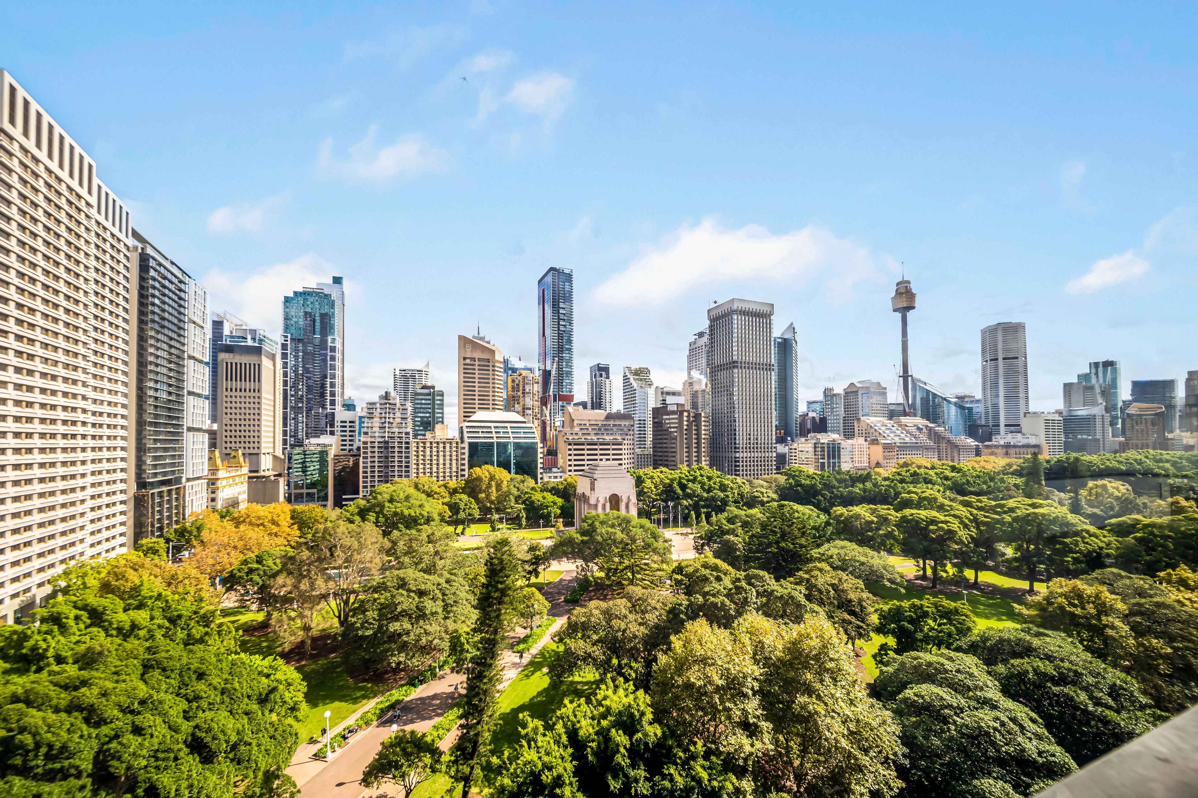 A cityscape with modern high-rise buildings and a park area with pathways and trees.