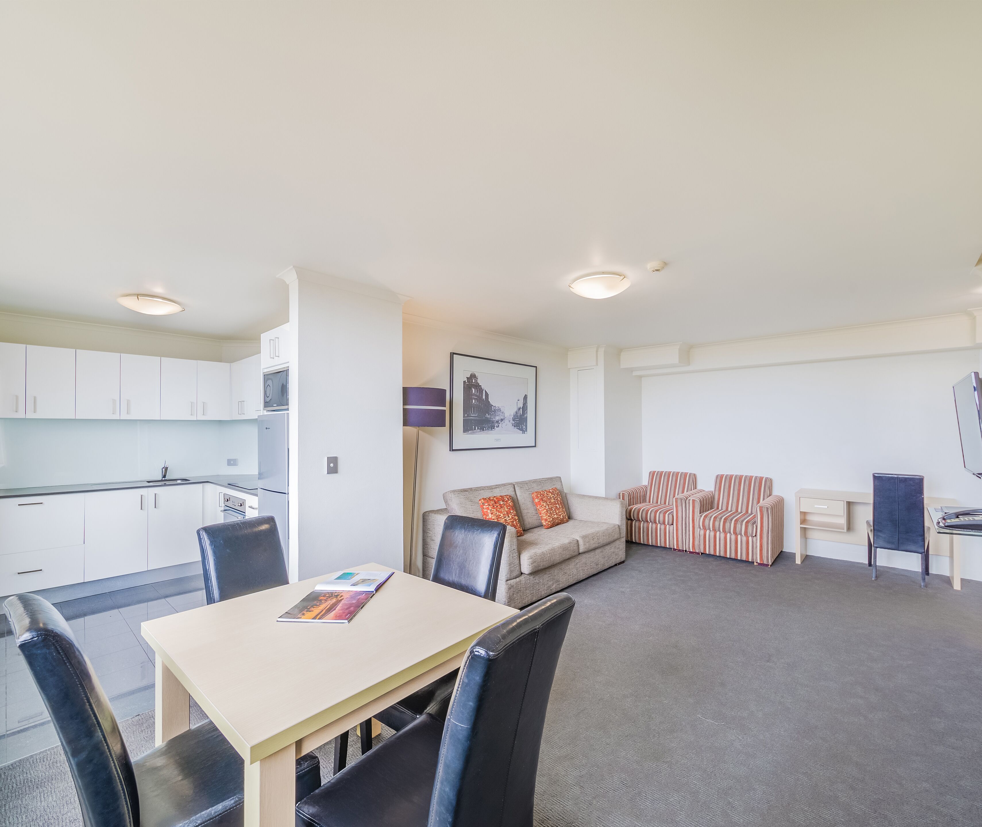 A compact living space with a kitchenette, a dining area, and a seating area with a sofa and chairs.