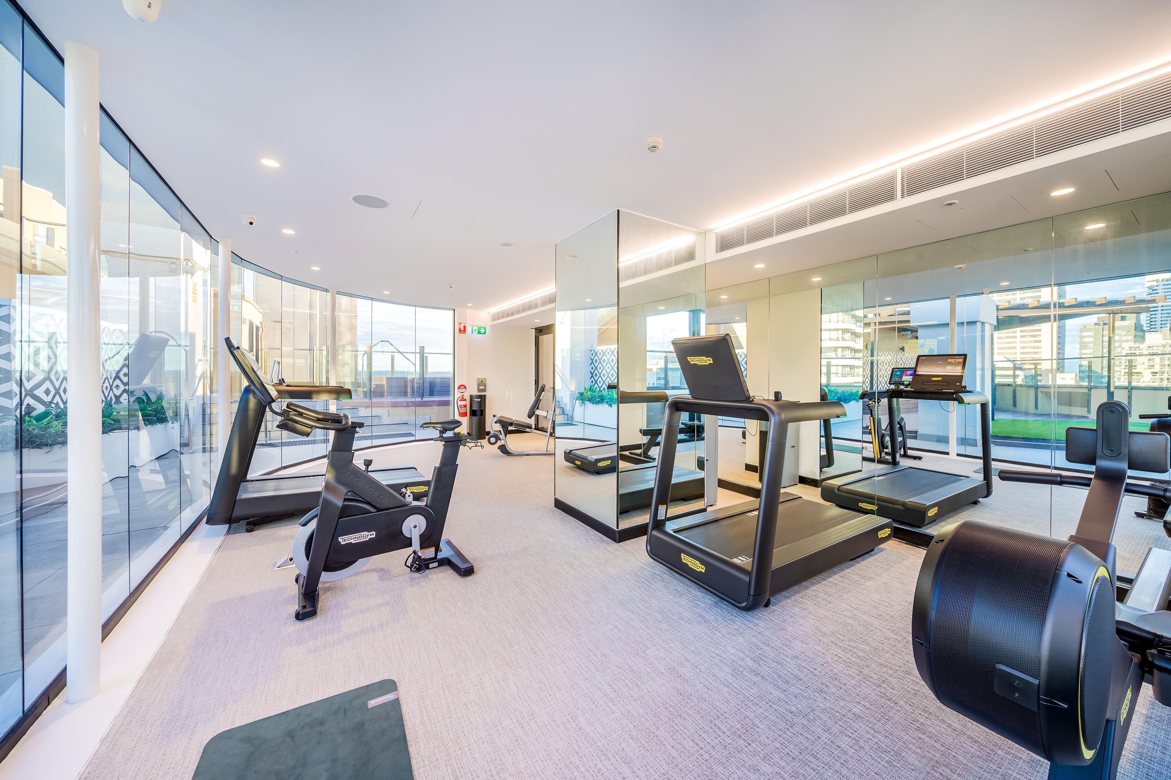 A modern gym with treadmills, elliptical machines, and exercise equipment.