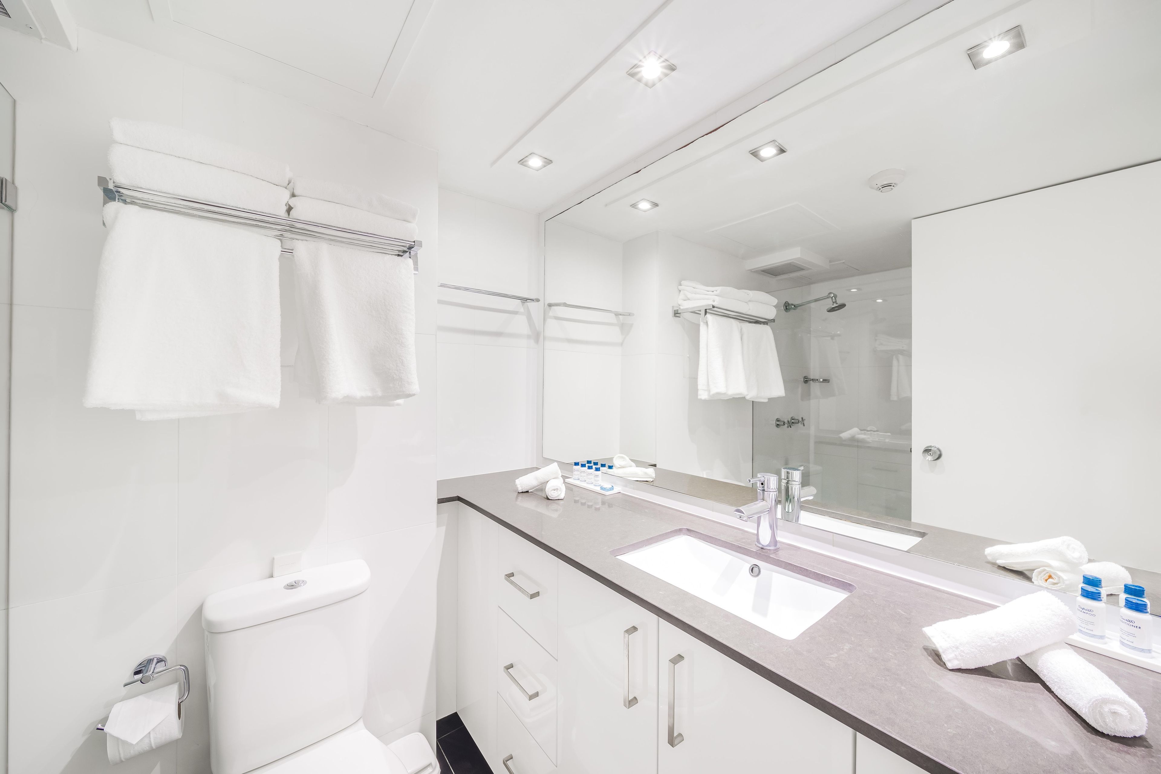 A modern bathroom with a sink, mirror, towel rack, and shower.