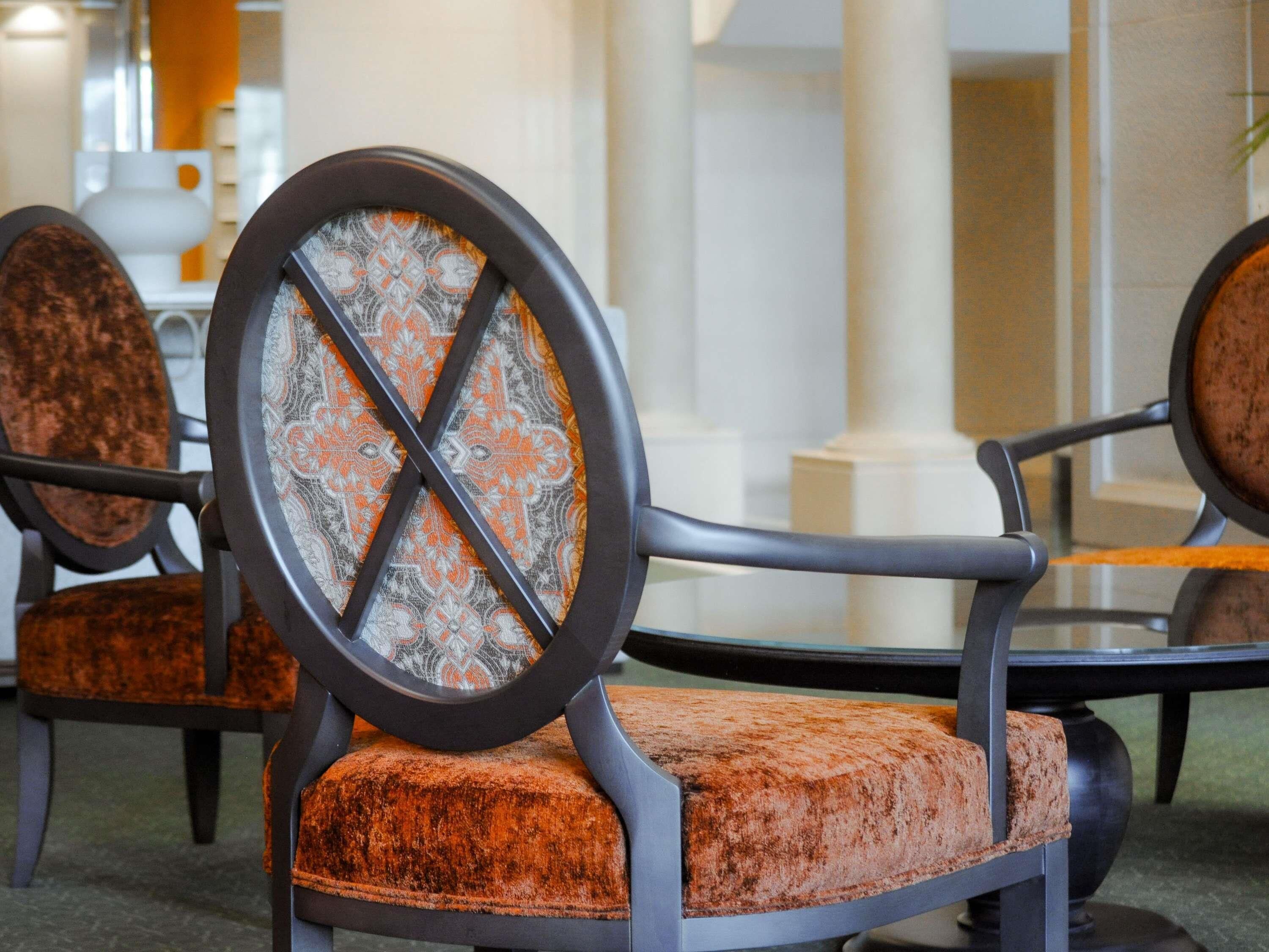 A modern interior with a round, cushioned chair with a patterned backrest and a dark frame.