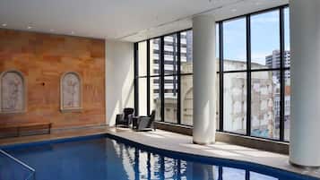 An indoor swimming pool with clear views of the city through large windows.