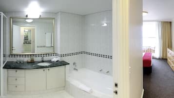 A modern bathroom with a large mirror, a sink, a bathtub, and a toilet.