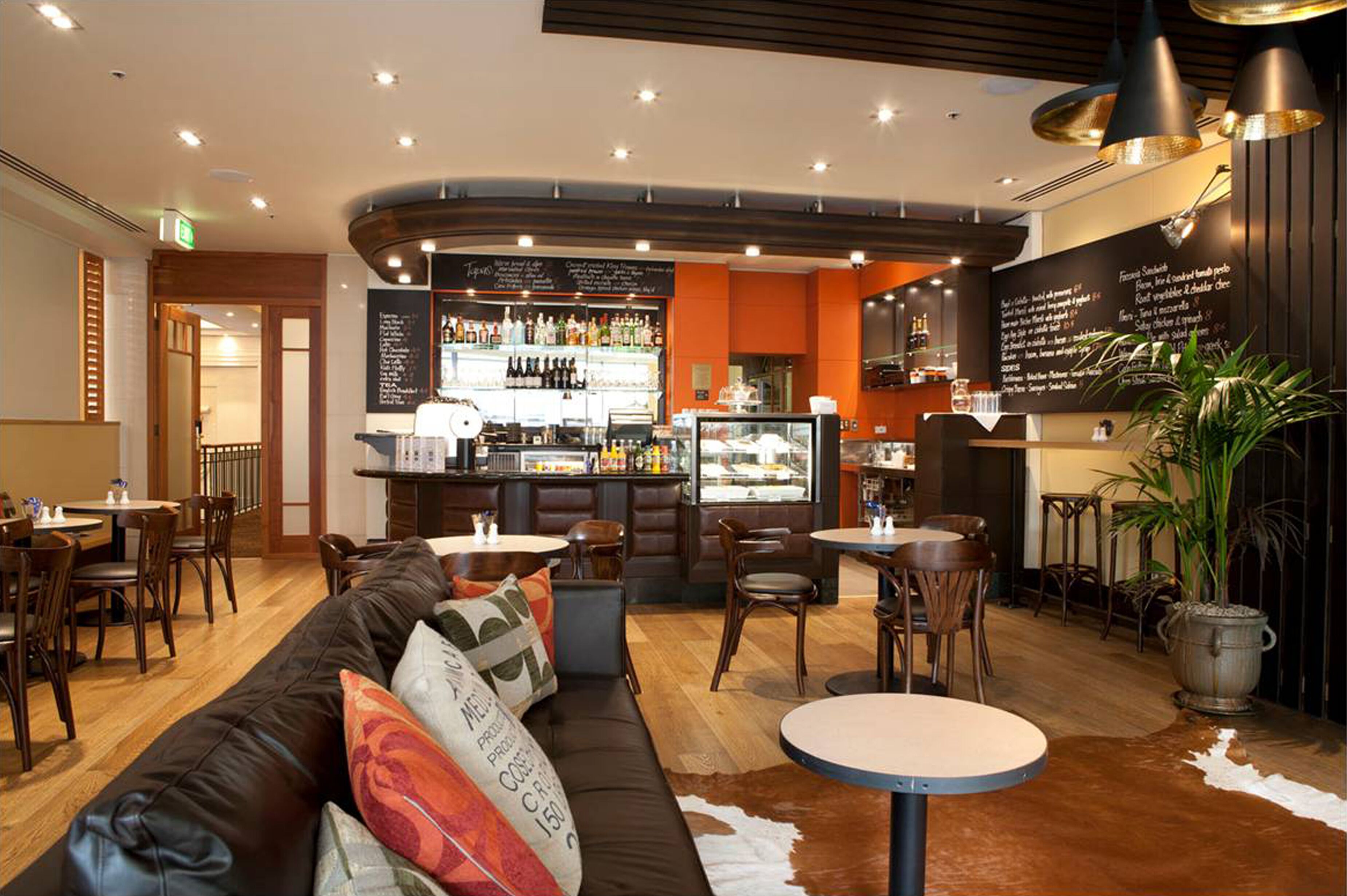 A restaurant with a bar area, wooden furniture, and a menu board.