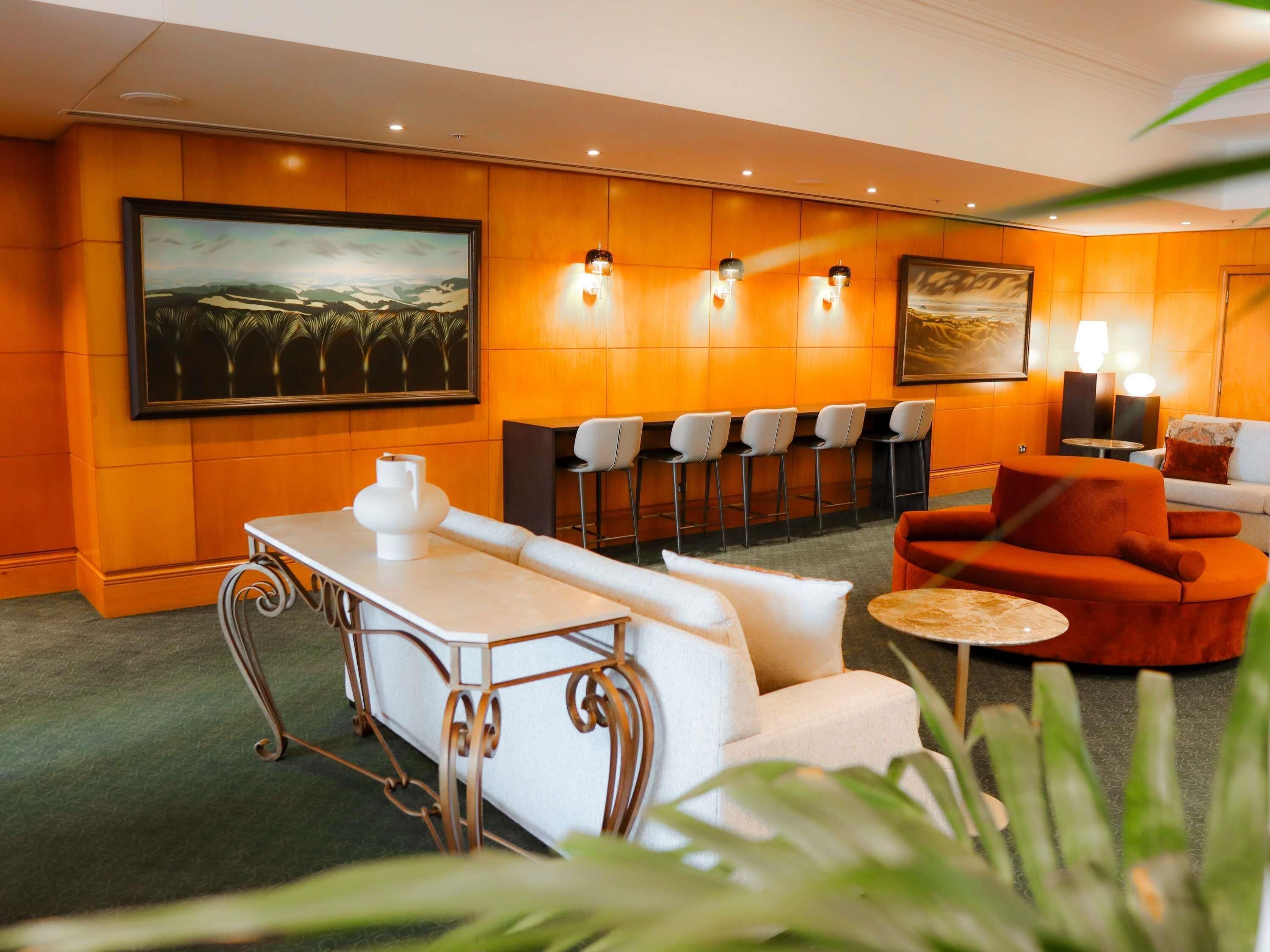 A hotel lobby with a bar area, seating, and artwork on the walls.