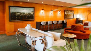 A hotel lobby with a bar area, seating, and artwork on the walls.