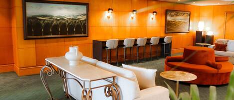 A hotel lobby with a bar area, seating, and artwork on the walls.