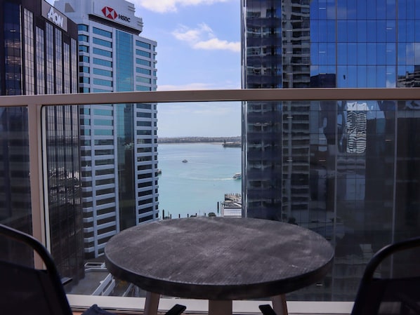 A view from a balcony with a round table and chairs, overlooking a body of water with boats and high-rise buildings in the background. - The Sebel Quay West Auckland (Auckland)