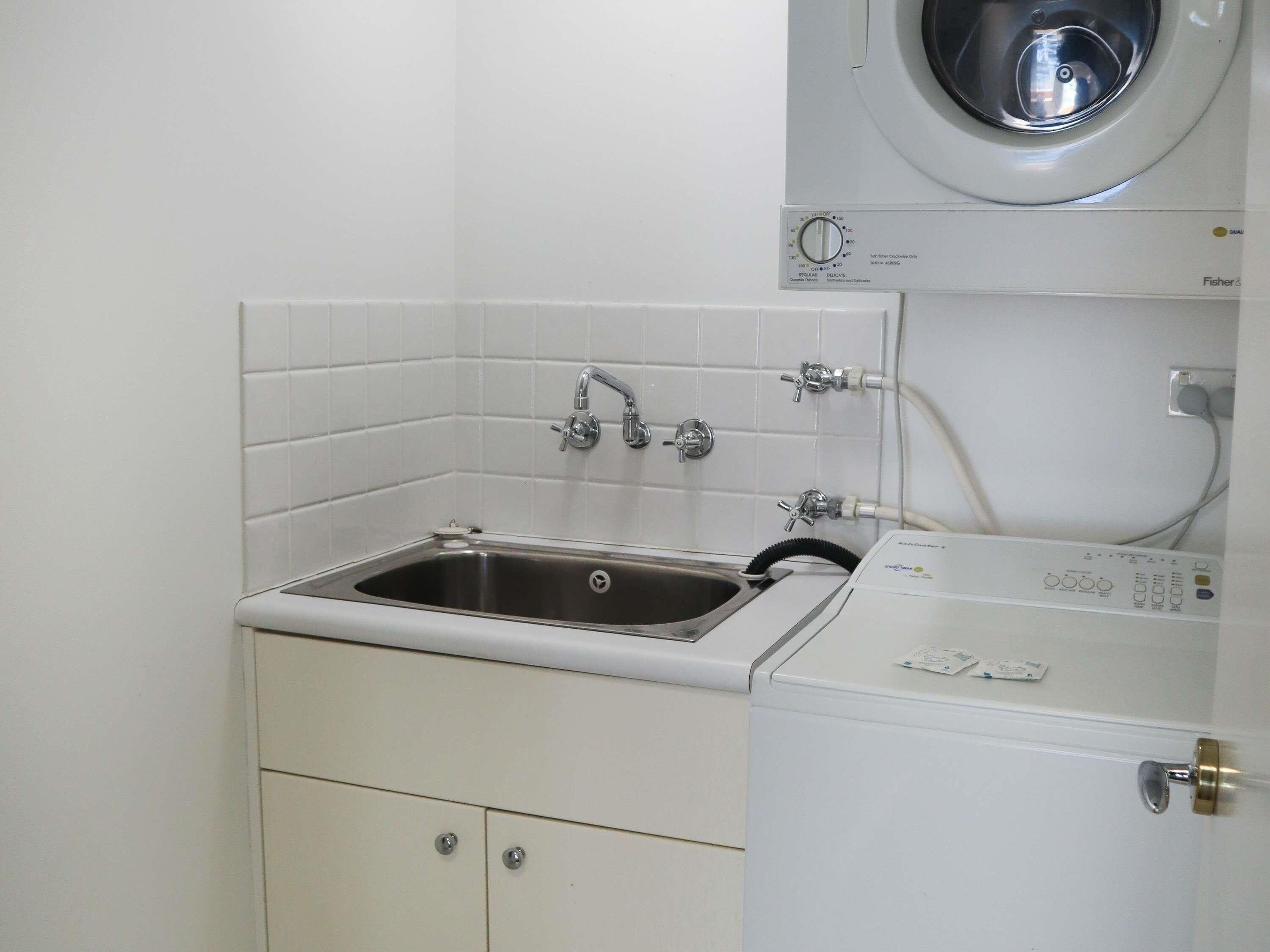 Een kleine wasruimte met een wasbak, een wasmachine en een droger.