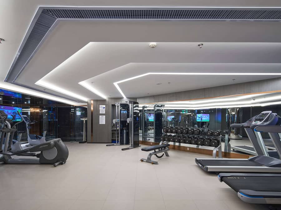 Un gimnasio moderno con cintas de correr, elípticas y pesas libres.