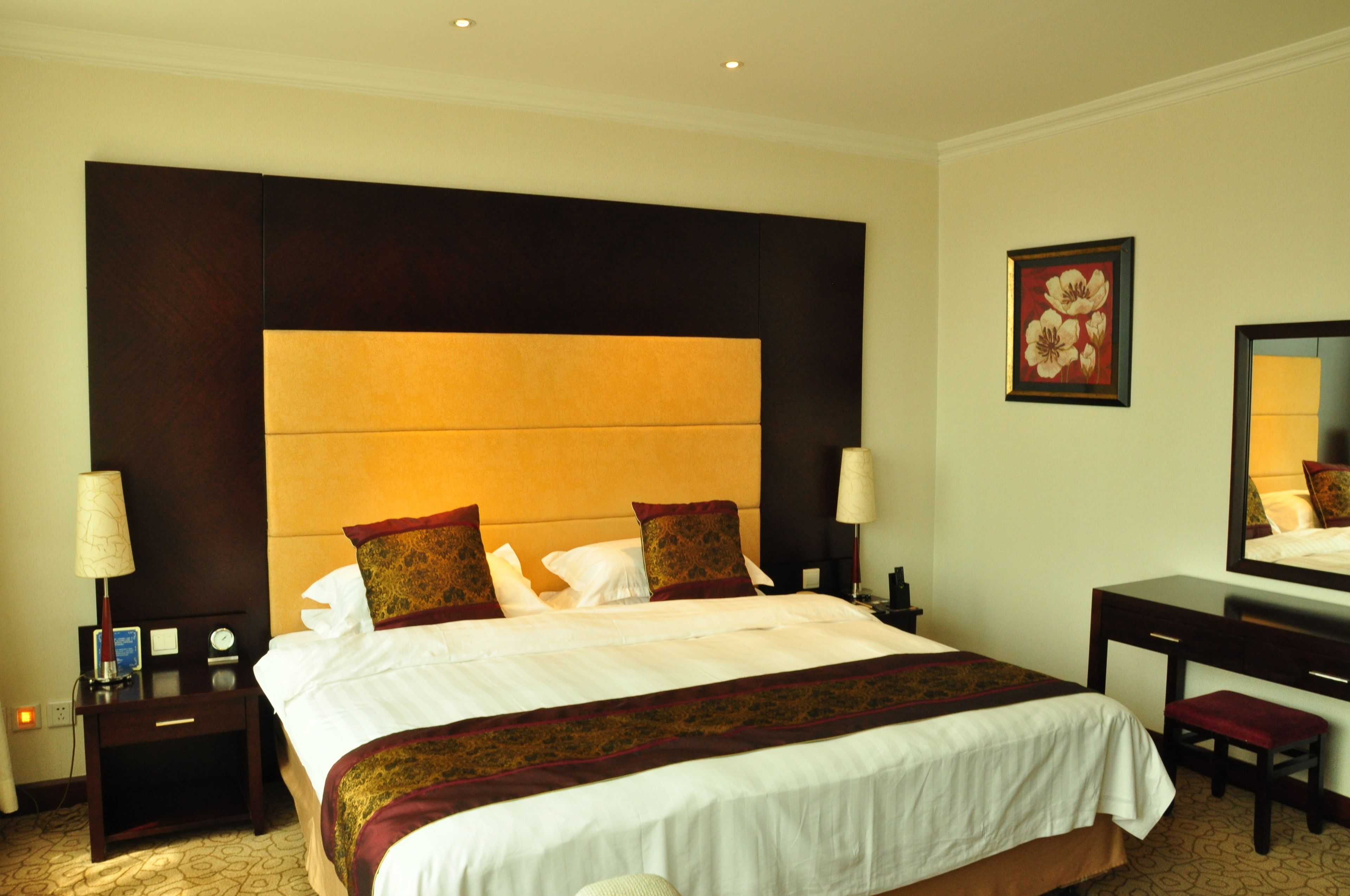 Une chambre d’hôtel avec un grand lit, deux tables de chevet, un bureau et une chaise.