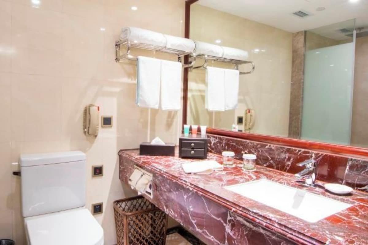 A modern bathroom with a marble sink, a large mirror, and a toilet.