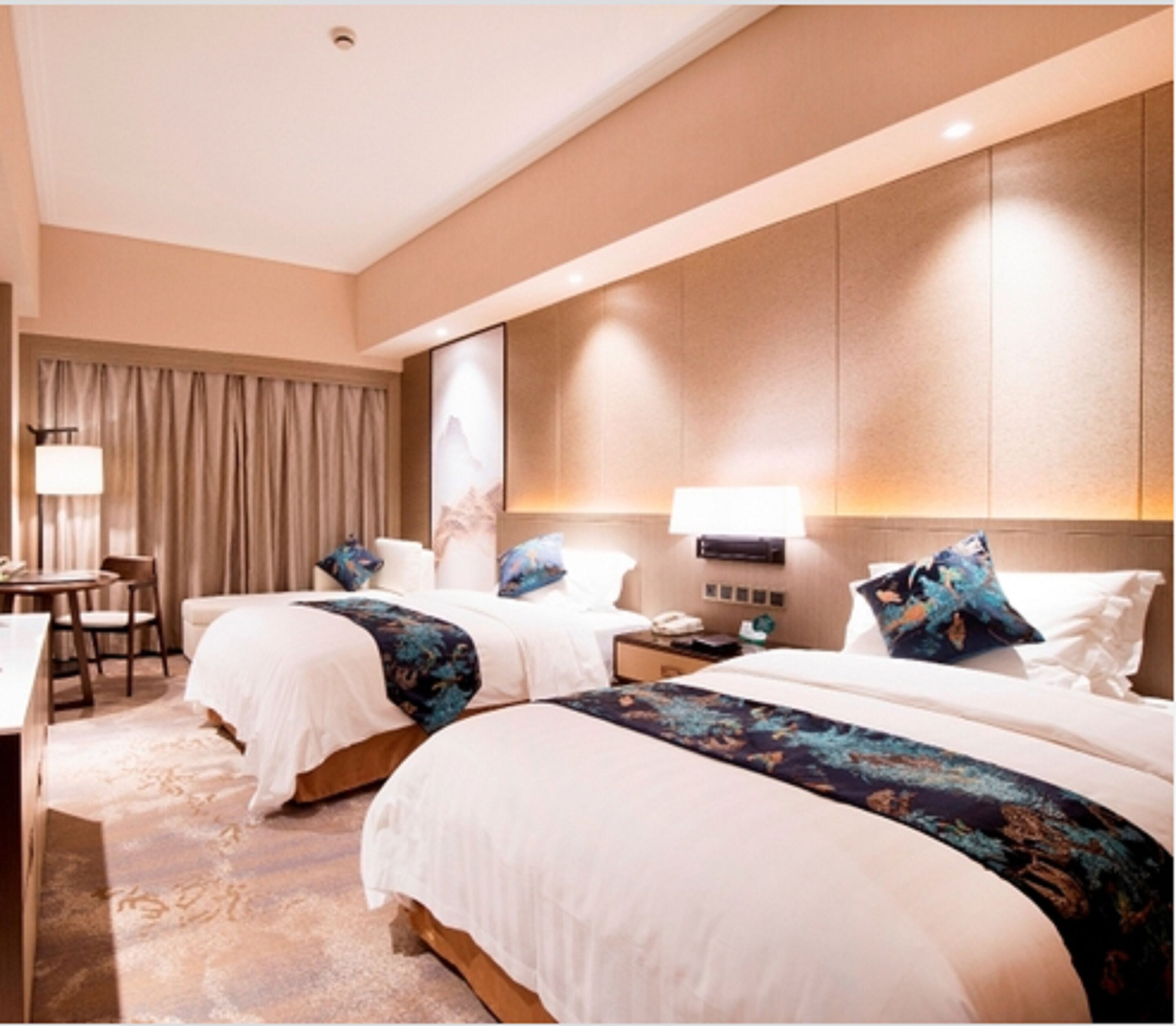 A hotel room with two beds, a desk, and a chair.