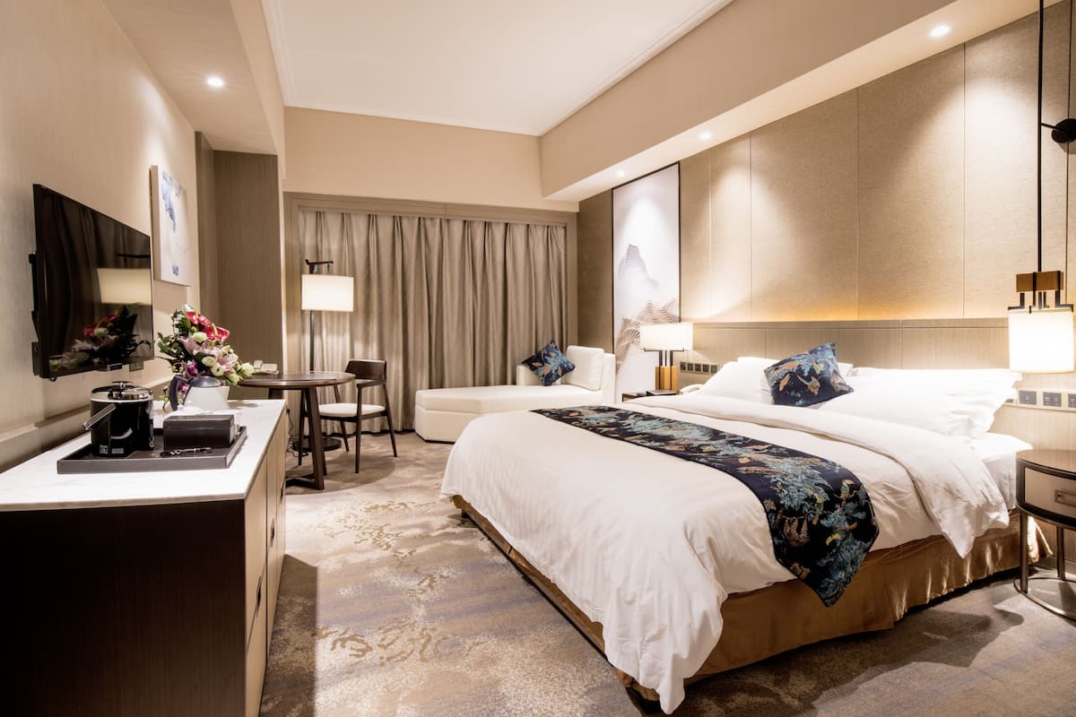 Una habitación de hotel moderna con una cama grande, un escritorio, una silla y una mesita.