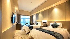 A hotel room with two beds, a desk, a chair, a TV, and a large window. - Jin Jiang Pine City Hotel (Shanghai)