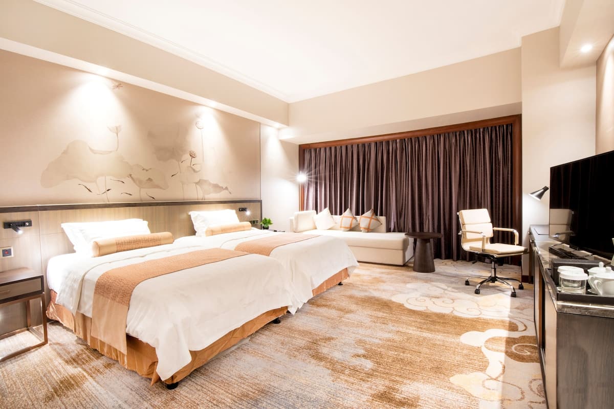 Una habitación de hotel con una cama grande, un sofá, un escritorio con una silla y un televisor.