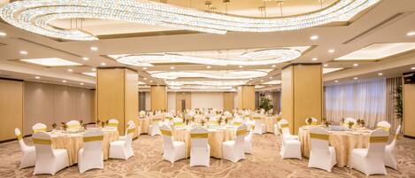 A banquet hall with round tables, white chairs, and gold sashes.