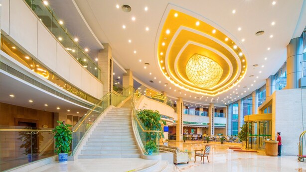 A spacious lobby with a central staircase, multiple levels, and a modern ceiling design. - Jin Jiang Pine City Hotel (Shanghai)