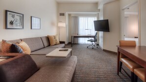 A hotel room with a sofa, a dining table, a TV, and a desk. - Residence Inn by Marriott Charlotte Uptown (Charlotte)