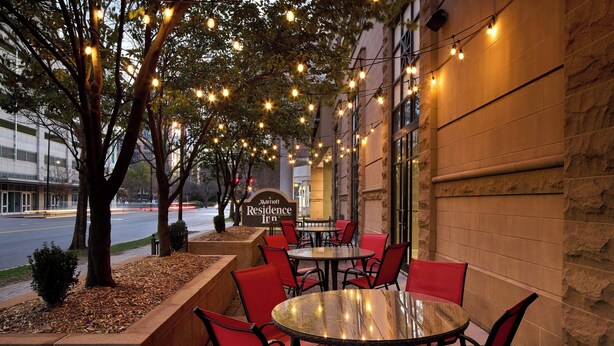 An outdoor seating area with tables and chairs, string lights, and a Marriott Residence Inn sign. - Residence Inn by Marriott Charlotte Uptown (Charlotte)