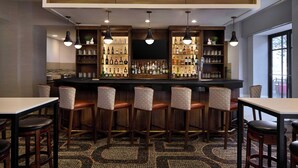 A bar area with a long counter, multiple stools, and shelves stocked with bottles. - Residence Inn by Marriott Charlotte Uptown (Charlotte)