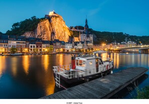 A waterfront cityscape with a prominent mountain, a church, and a row of colorful buildings along the river. - ibis Dinant Centre (Dinant)