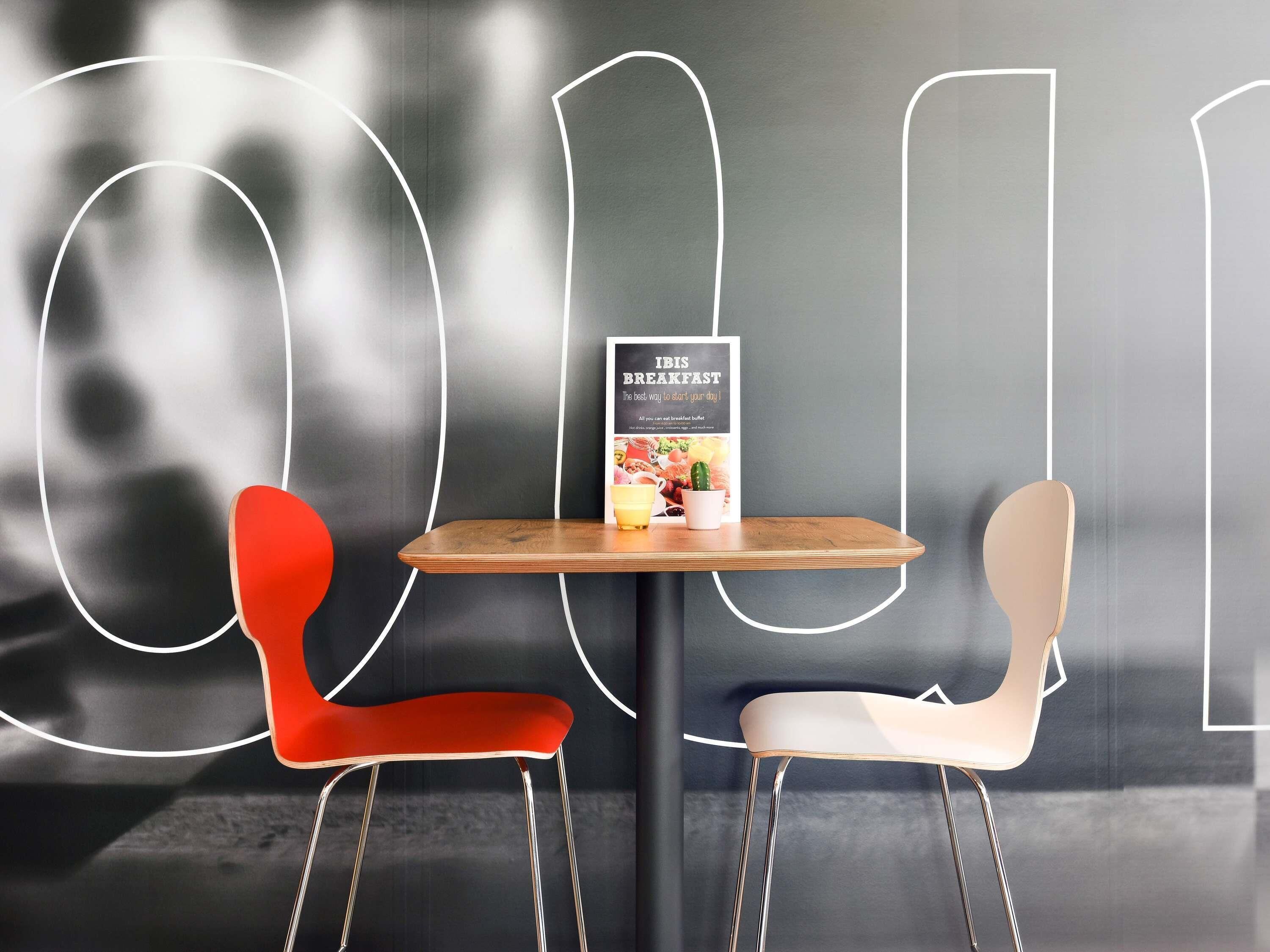 A modern dining area with two chairs, a table, and a menu stand.