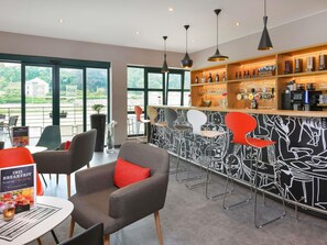 A modern bar area with a black and white mural, a variety of bottles, and a seating area with chairs and a table.