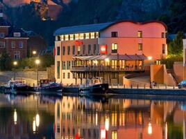 Un hotel con vista al agua, un balcón y un reflejo en el agua.