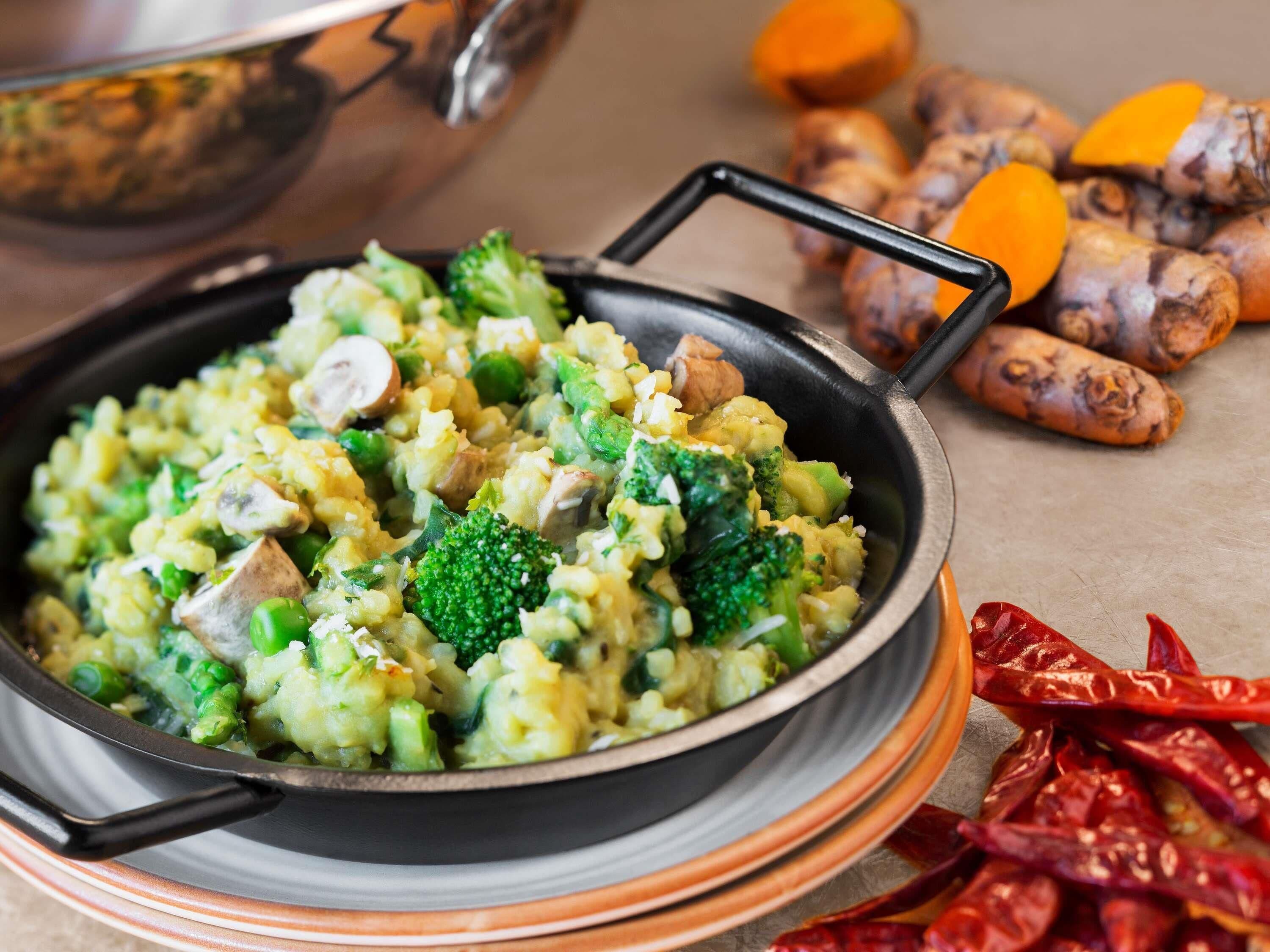 A pan of mixed vegetables with a handle, surrounded by whole spices.