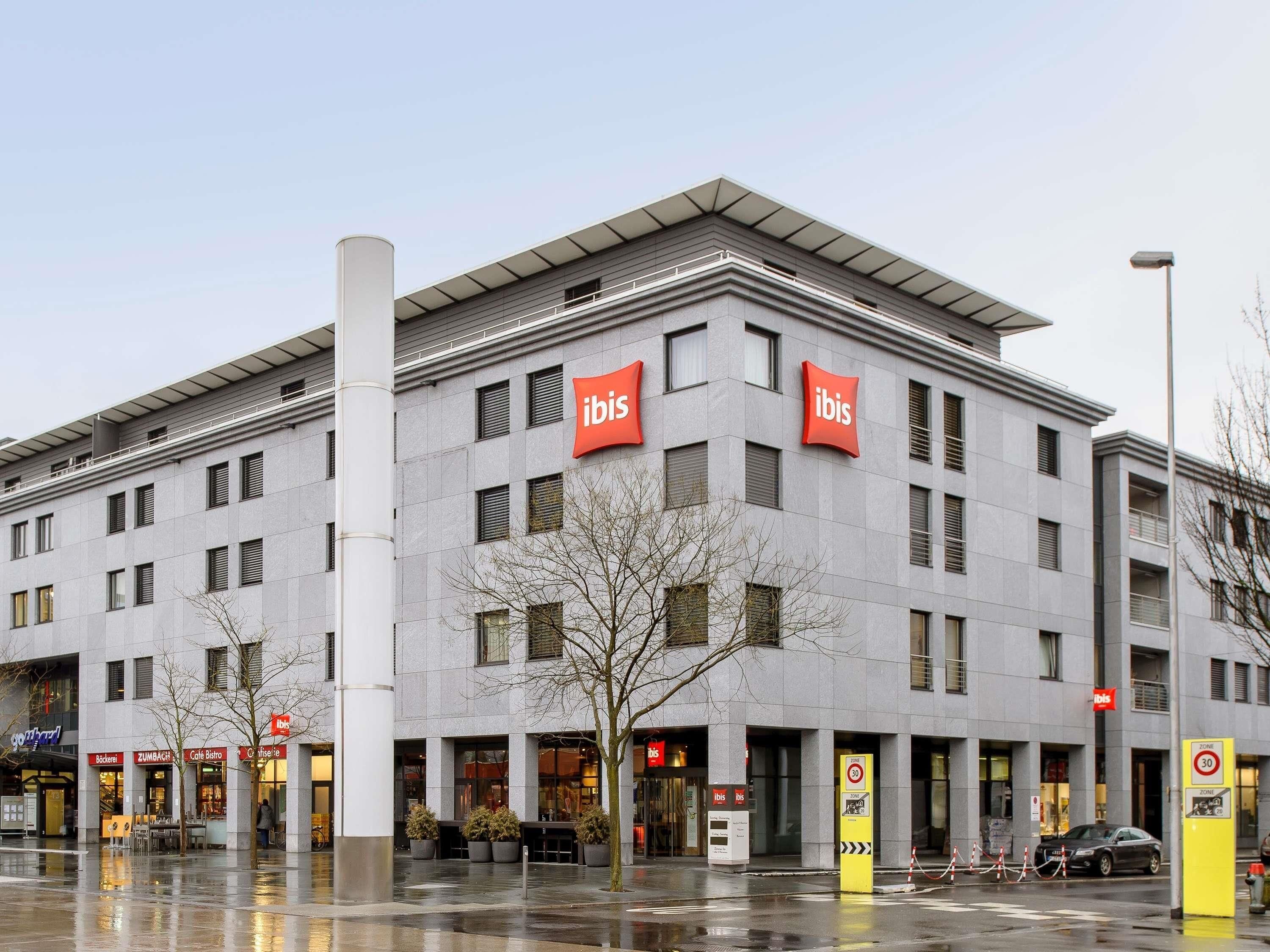 A modern building with multiple 'ibis' signs, indicating a hotel or similar establishment.