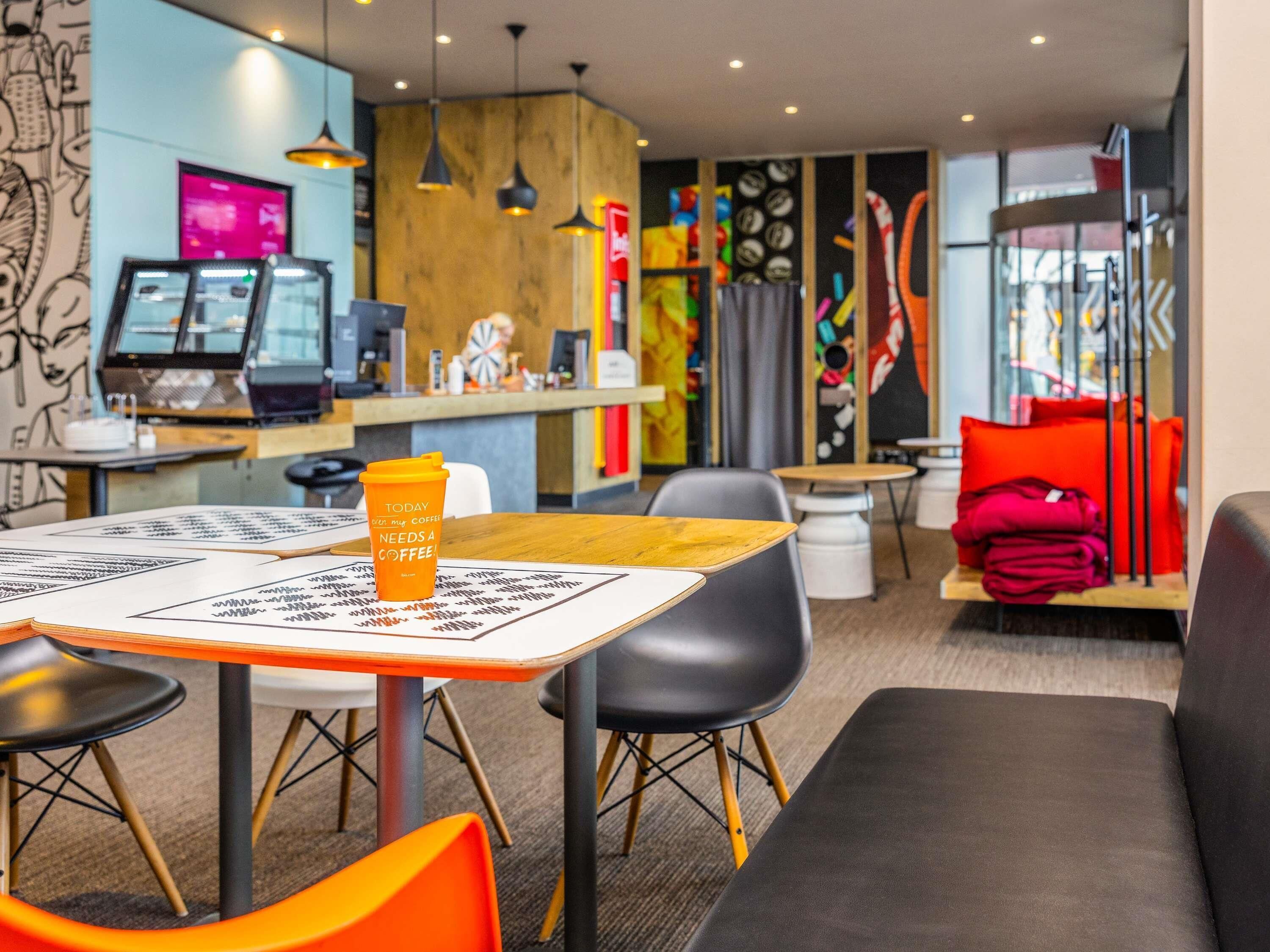 A modern cafe with a wooden counter, tables, and chairs, and a coffee cup on a table.